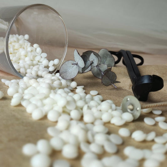 Soy wax spilling out of a metal container onto a wooden surface with a neutral background